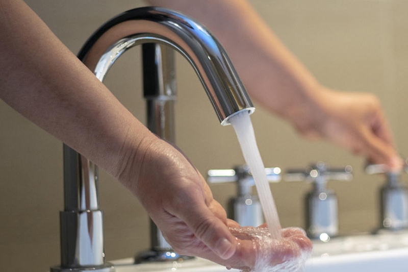 Hands turning on the water of bathtub.